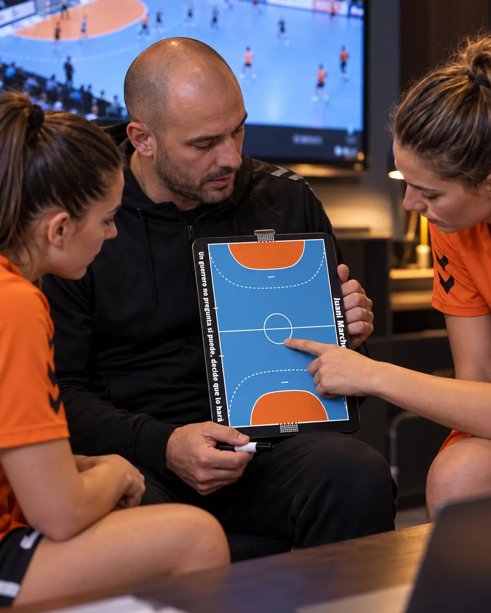 Un entraîneur de handball revoit la tactique sur la plaquette avec ses joueuses